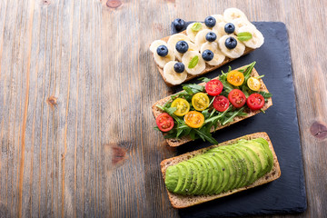 Wall Mural - Vegan rye wholegrain sandwich with avocado, arugula, banana and blueberries for healthy meal, vitamin and diet food