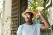 © wayhome.studio - People, leisure and lifestyle concept. Happy and relaxed young black European man in stylish clothing adjusting brims of his hat smiling broadly while flirting with pretty woman at sidewalk cafe