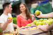 © luckybusiness - green apple in hand seller at a market stall.