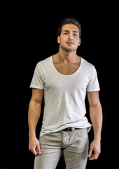 Brown eyed, black haired latin man standing in studio, looking to a side, hands in pockets, isolated on white background