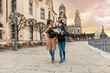 © EdNurg - Two charming cheerful women are walking with a map along Dresden Street, Germany. The concept of love and friendship in travel