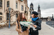 © EdNurg - Two charming cheerful women are walking with a map along Dresden Street, Germany. The concept of love and friendship in travel