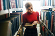 © yossarian6 - Young woman reading a book in library
