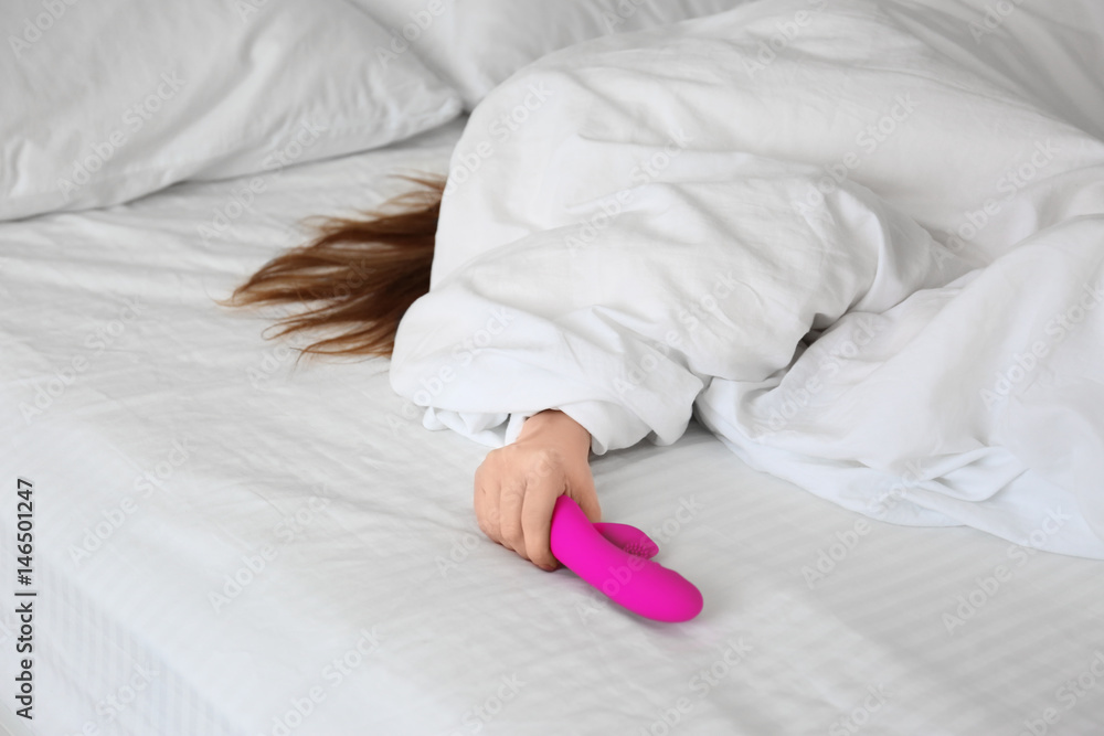Woman holding dildo in bed
