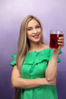 Beautiful young woman with glass of fresh juice on color background