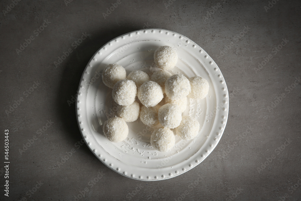 Plate with coconut candies on table