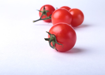 Sprig of fresh tomatoes with green leaves isolated on white background.