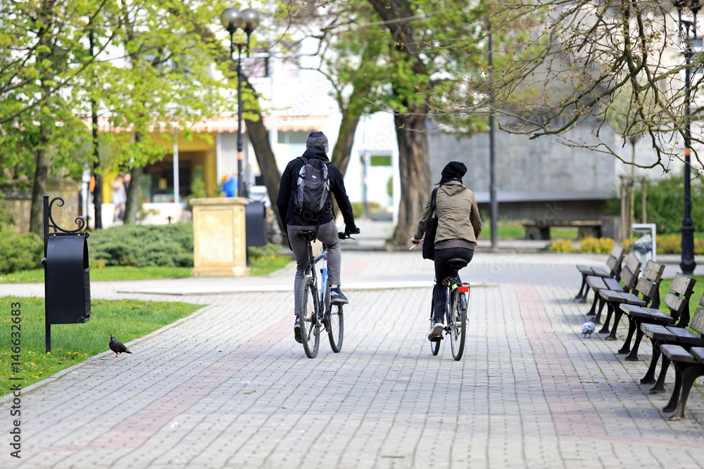 Szczęśliwa para, dziewczyna i chłopak jadą na rowerze w parku.  - obrazy, fototapety, plakaty 