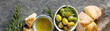 Olivier oil with fresh herbs and bread. Gray background. Italian and Greek national food. Top view