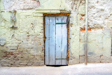 Wall Mural - retro wooden door on a cracked concrete vintage brick wall background 