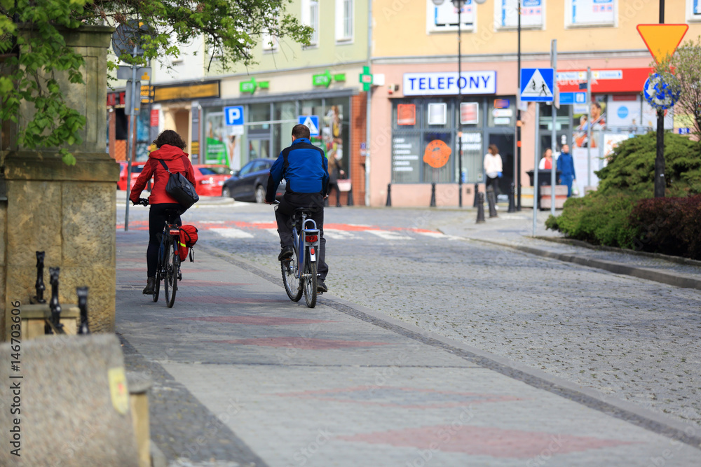 Szczęśliwa para, dziewczyna i chłopak jadą na rowerach przez miasto. - obrazy, fototapety, plakaty 