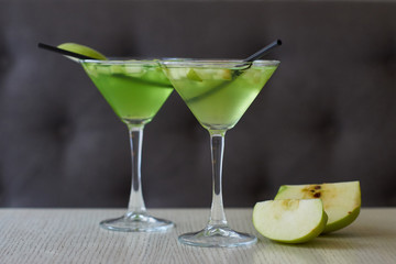 Two glasses of apple martini and apple slices on table in cafe