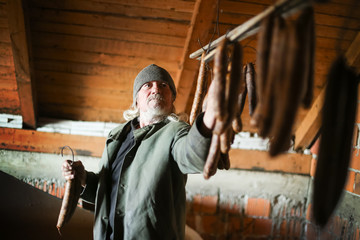 Man drying sausages in attick