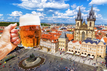 Wall Mural - Hand with a mug of beer on the background of the Old Town Square in Prague