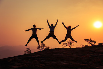 Group of tourists jumping on top of the mountain.