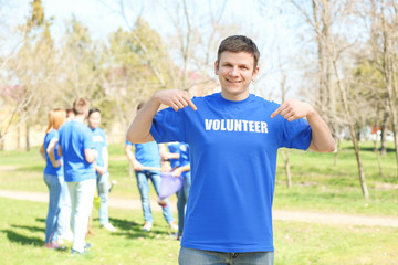 Canvas Print - Handsome young volunteer with team outdoors