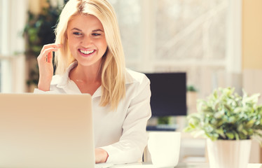 Wall Mural - Happy young woman sitting at her desk