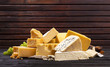 Various types of cheese on black wooden table.