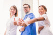 © Myroslava - Three smiling happy doctors stand and show thumbs up outdoor