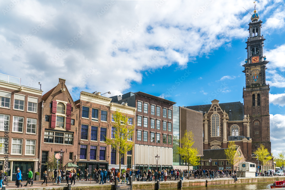 Amsterdam, The Netherlands, April 22, 2017: Tourists waiting in line to get in to the Anne Frank house in Amsterdam next to the Westertoren - obrazy, fototapety, plakaty 
