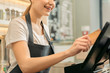 © Yakobchuk Olena - Cute female cashier holding credit card near monitor
