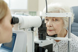 Fototapeta  - Young female ophthalmologist using apparatus