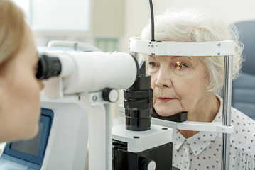 Wall Mural - Young female ophthalmologist using apparatus