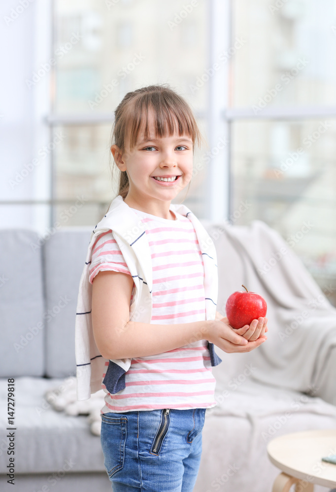Happy schoolgirl standing with apple at home