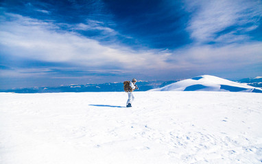 Army serviceman in winter camo somewhere in the Arctic. He wears chest rig, backpack, suffers from extreme cold, strong wind, but endures while mission continues, running moving across snow desert