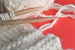 White wool knitting needles and handmade knits on bright orange