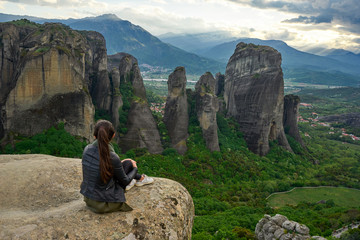 Girl enjoys the view of great and high rock in Meteora, Thessaly, Greece