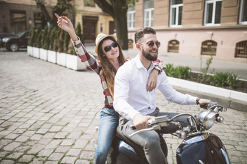 Beautiful young couple riding scooter along a street and smiling. toned