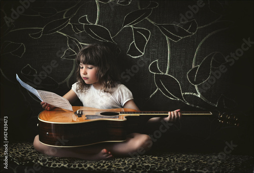 mala-dziewczynka-z-gitara-i-notatkami-na-ciemnym-tle