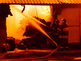 Wall Mural - Firefighters extinguish a fire in a burning warehouse