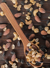 Wall Mural - Spoon with nuts and raisins on a wooden background. Top view.