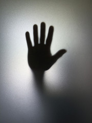Wall Mural - man or woman showing stop gesture hand silhouette through frosted glass