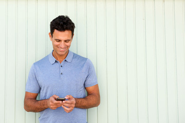 Wall Mural - cool middle age man smiling and looking at cellphone