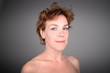 © Roberts Images - Beautiful red haired aging mature female model against a grey background.