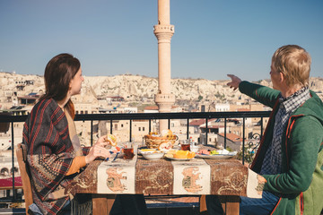 Couple eat traditional turkish breakfast on rooftop with city view