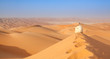arab man in traditional outfit sitting over a Dune in arabian desert and enjoying the peaceful landscape of the empty quarter