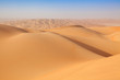 Arab man in traditional outfit sitting on a dune in the empty quarter of the arabian Desert