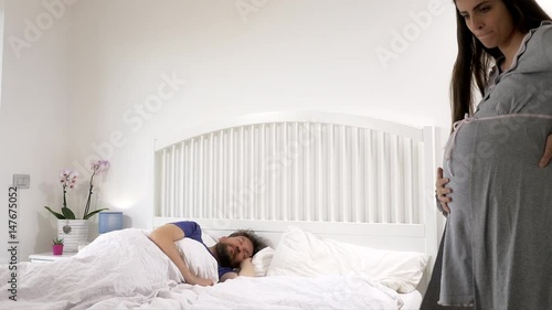 Angry nervous pregnant woman waking up husband in bed