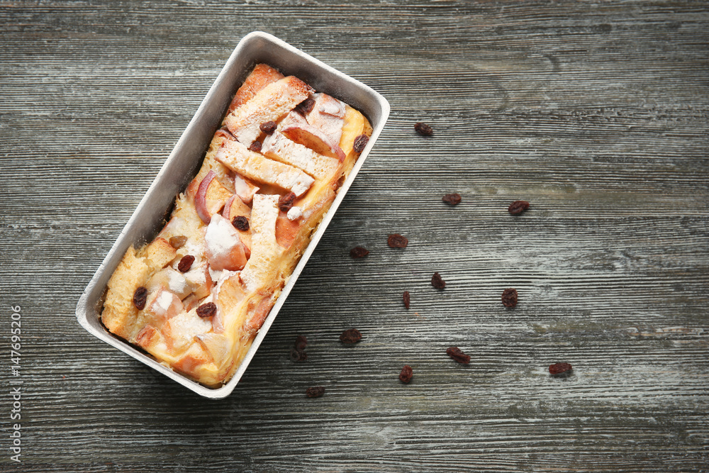 Freshly baked bread pudding in casserole dish on wooden table