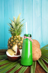 Wall Mural - Bottle with fresh coconut milk and pineapple on wooden table