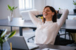 © bnenin - Portrait of beautiful happy smiling young designer woman sitting in headphones at office desk, working in beautiful interior.