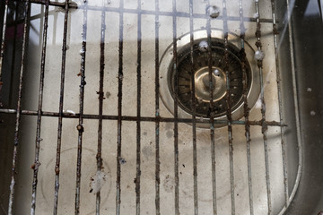 The surface of a filthy grill rack submerged in kitchen sink. Cleaning of premises and equipment in the food industry or house with food and other similar places. 