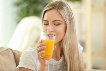 Poster - Beautiful young woman drinking fresh juice at home