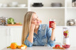 © Africa Studio - Beautiful young woman with glass of fresh juice in kitchen