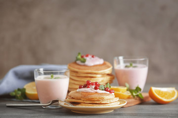 Wall Mural - Delicious pancakes with yogurt and cranberry on table against blurred background