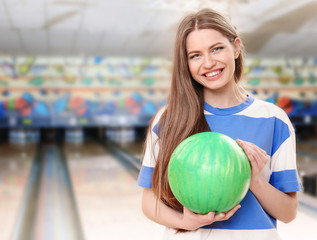 Wall Mural - Beautiful young woman with ball in bowling club